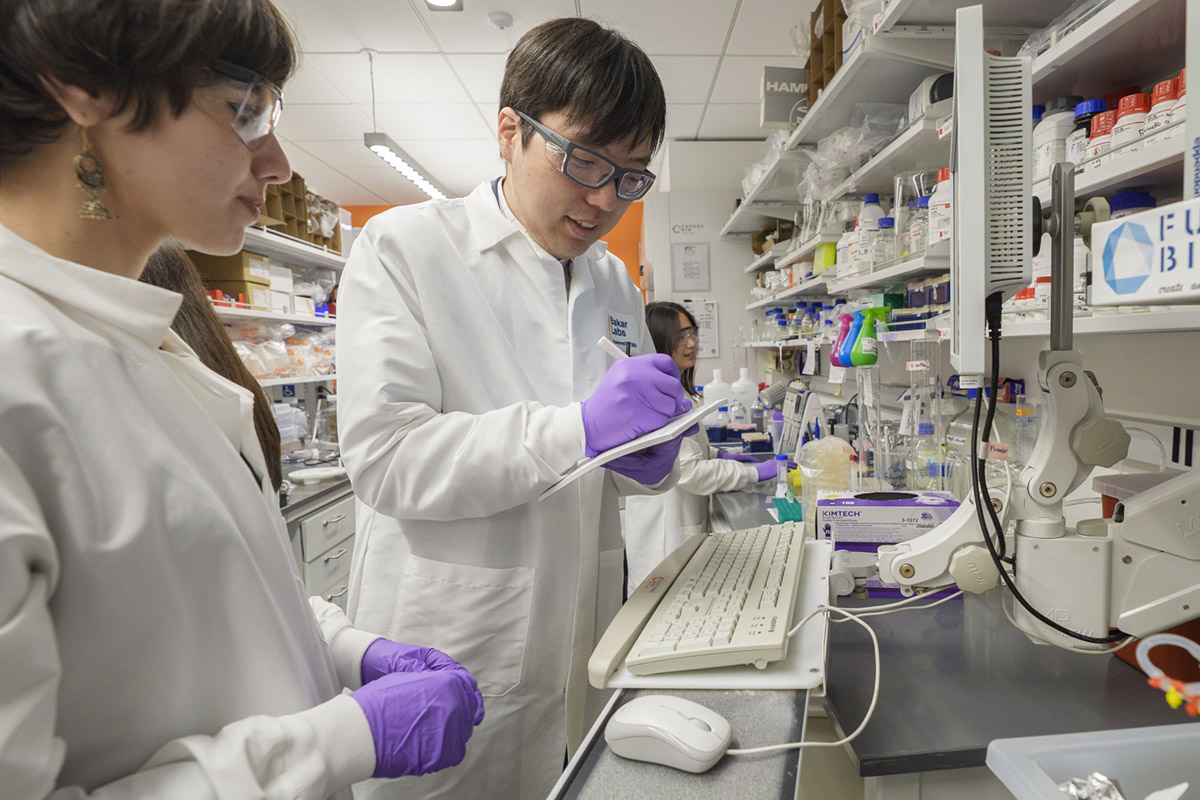 Two scientists in white lab coats at the lab bench