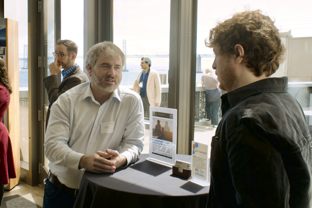 Gigacrop CEO Chris Eiben stands at a table talking to an attendee.