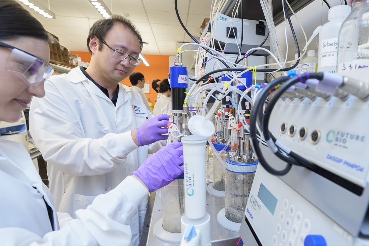 Two scientists in lab coats work at a biofermentation station